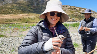 Alana Kimber holding a black fronted tern chick. 