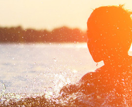 Boy in water at sunset